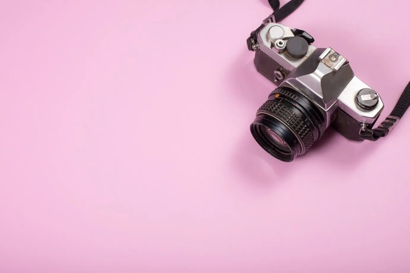 Old-fashioned camera on a pink backdrop